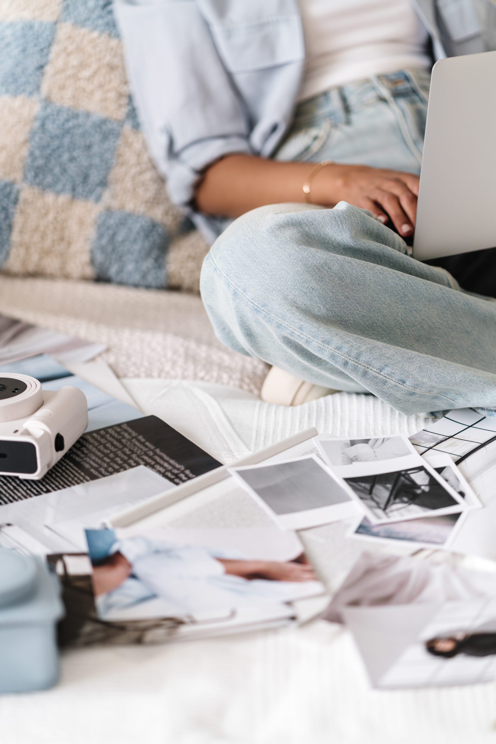 Woman working on a laptop with mood board photos laid out, reflecting the use of Myers-Briggs personality test in business.