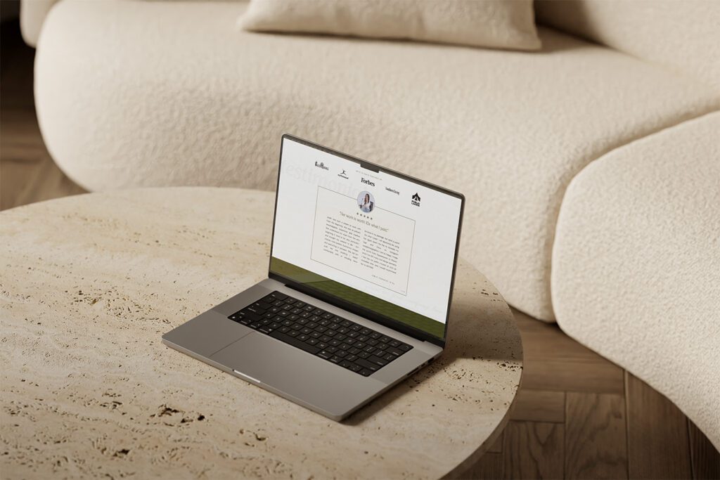 A laptop sits on a table in front of a couch, illustrating a workspace showcasing how to ask for client testimonials for your website