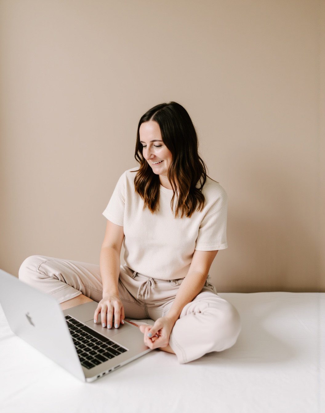 Jordin Brinn, custom website designer sitting on the floor working on her Macbook pro