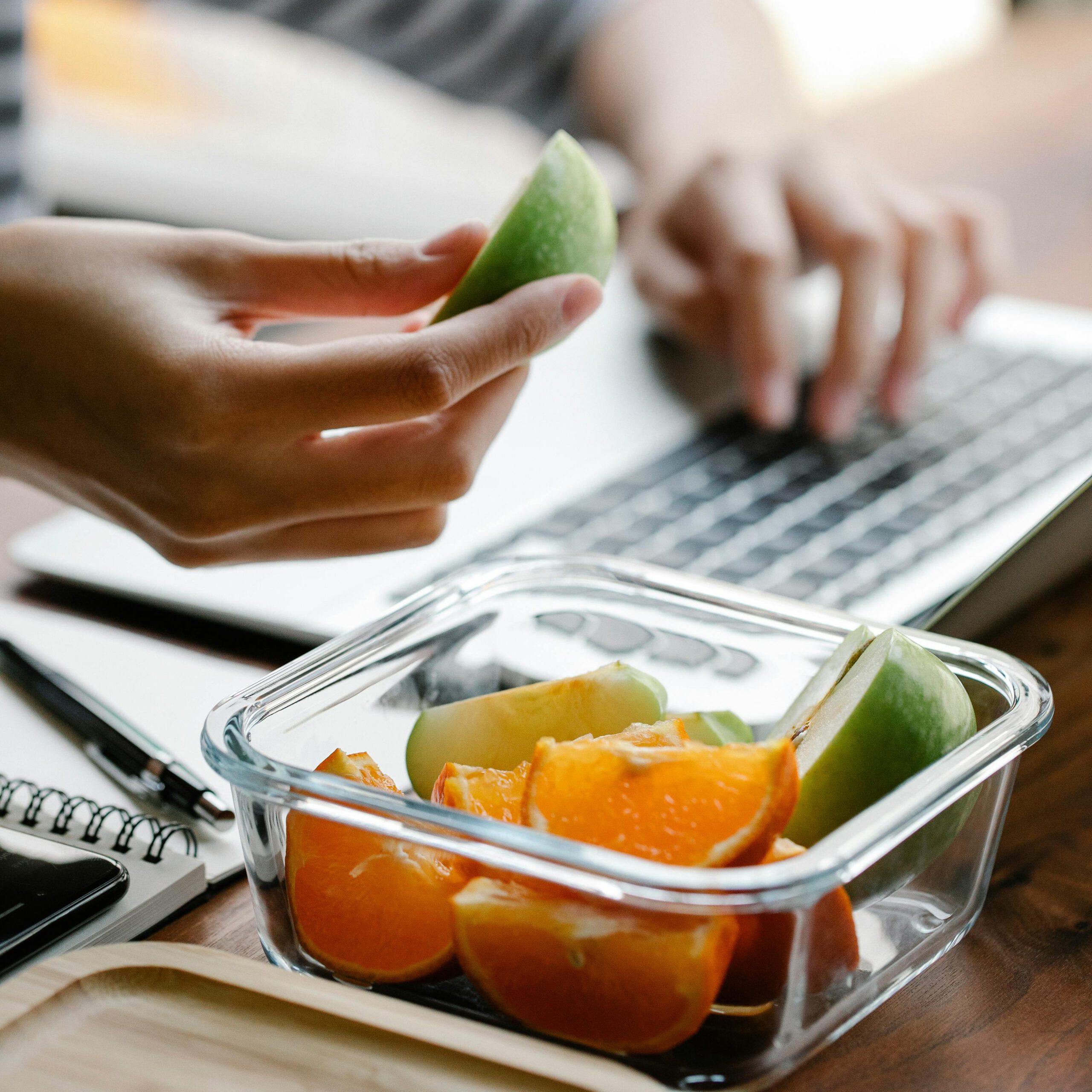 Woman on a laptop eating fruit
