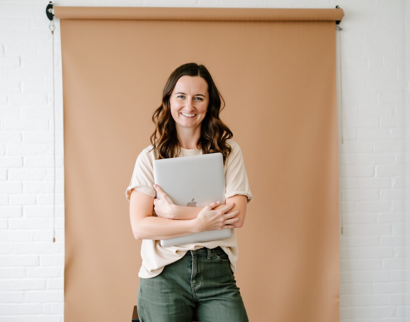 Showit Website Designer, Jordin Brinn, holding a laptop smiling at the camera