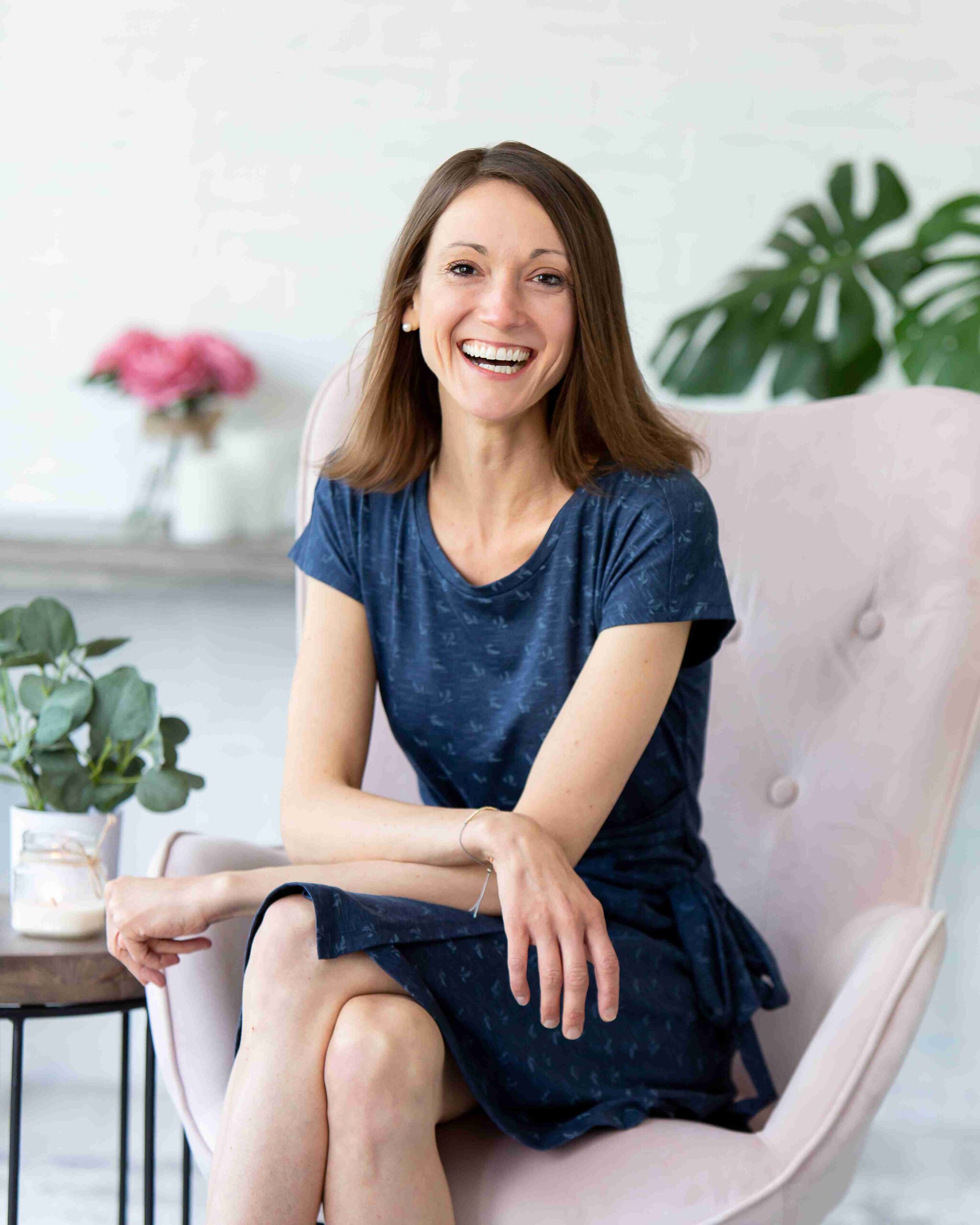 A woman sitting in a chair, smiling and laughing joyfully, radiating happiness and warmth.