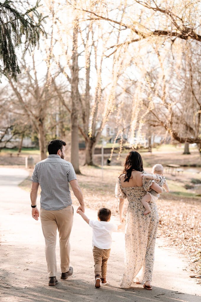 A family enjoying a sunny day in the park, posing for photos together amidst green trees and grass.