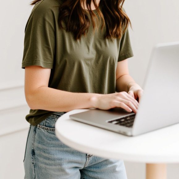 Woman in a green shirt typing on a macbook