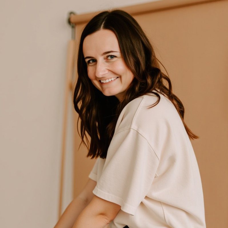 Headshot of website designer, Jordin Brinn, in a tan shirt smiling over her shoulder looking at the camera.