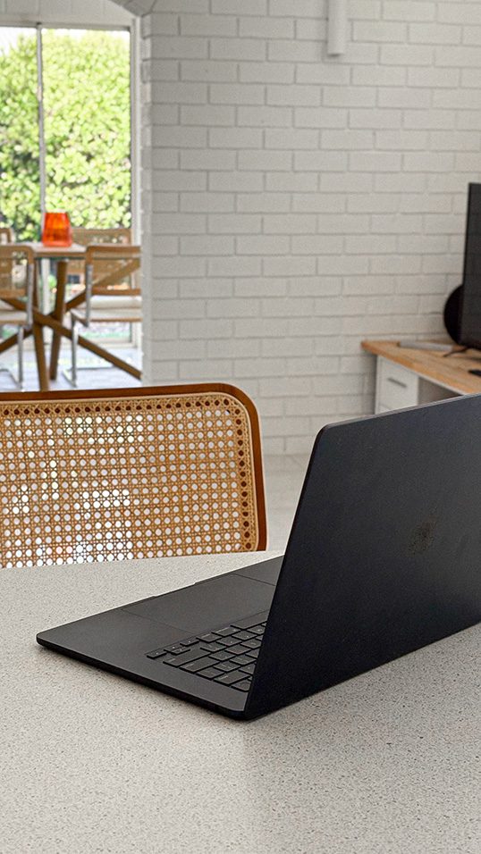 A laptop placed on a kitchen table, surrounded by a cozy home environment.