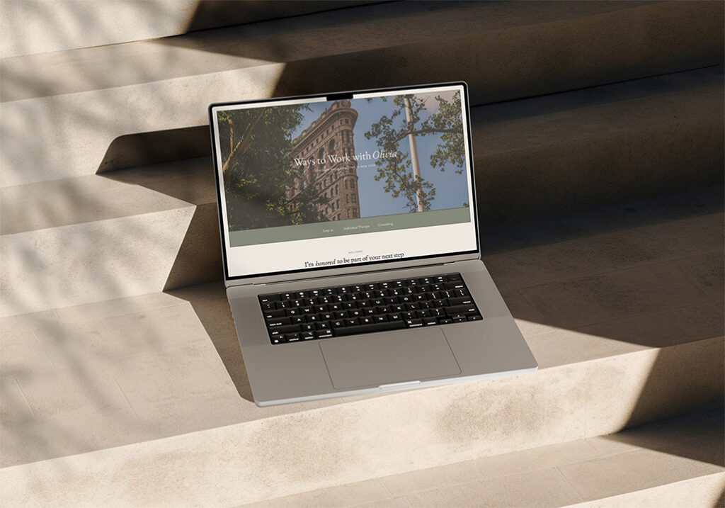 Elevated website design shown on a macbook pro resting on steps with outdoor shadows.