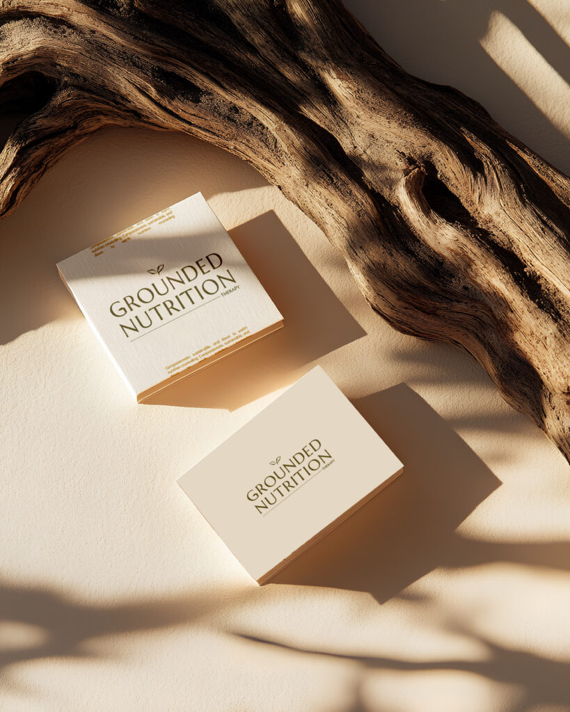 Warm sunlight falls on “Grounded Nutrition” booklets beside textured driftwood, creating earthy shadows and a calm, natural wellness mood.