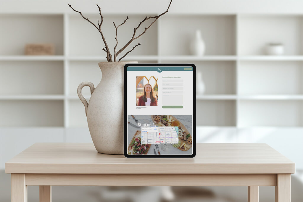 Tablet displaying a lifestyle website with a woman’s portrait and colorful content, beside a rustic vase with branches on a wooden table.