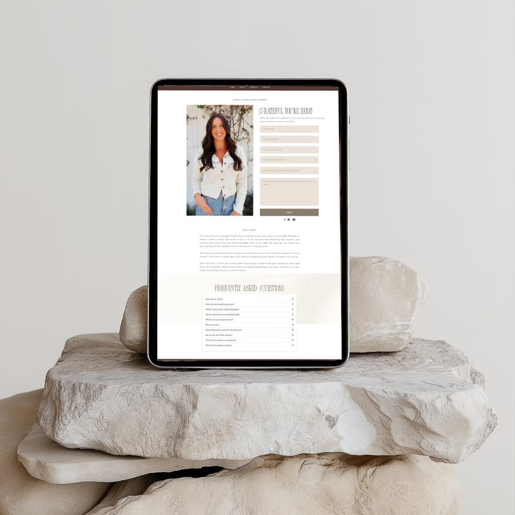 A black tablet on stacked pale stone slabs displays a fashion model and clothing details on a clean shopping page, conveying a calm, minimalist retail aesthetic.