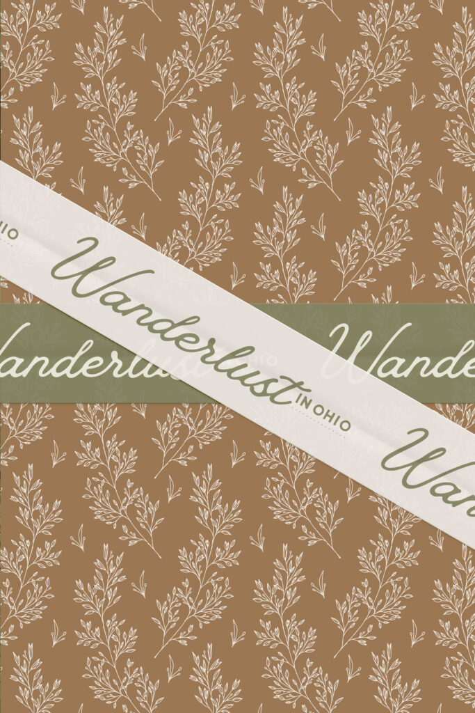 Warm brown gift wrap features repeating cream botanical sprigs and crossed olive and ivory ribbons printed with cursive “Wanderlust,” creating a rustic, elegant feel.