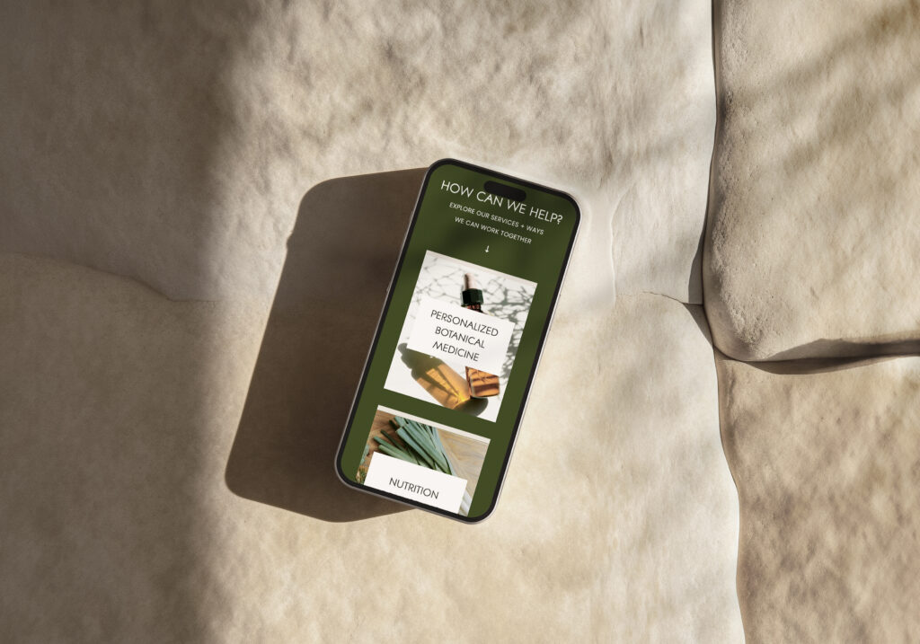 A smartphone on rumpled cream fabric displays a muted green wellness webpage with “How can we help?” and sections on personalized recovery and nutrition, in warm sunlight.