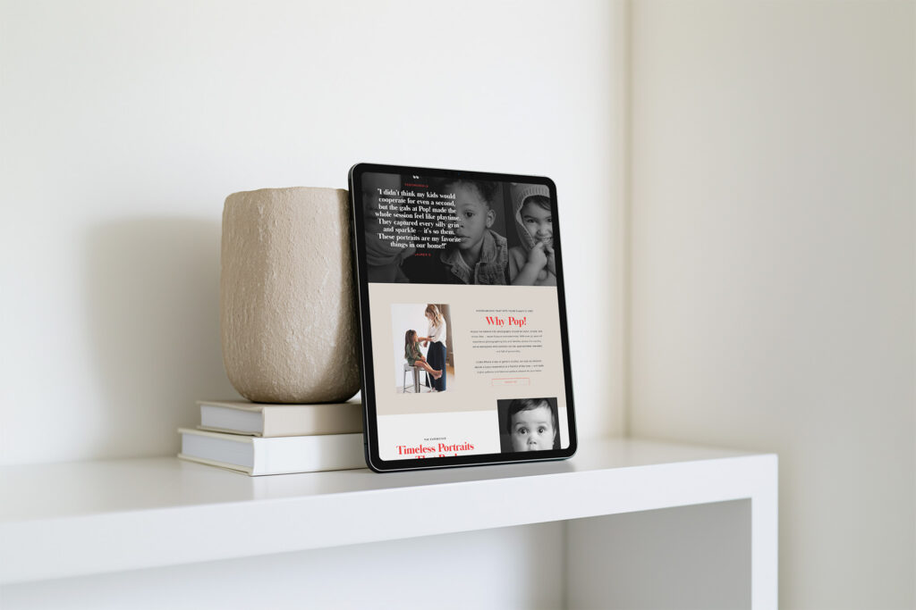 Tablet displaying a family-focused webpage with children’s photos rests against a beige vase and books on a white shelf, creating a calm, modern scene.
