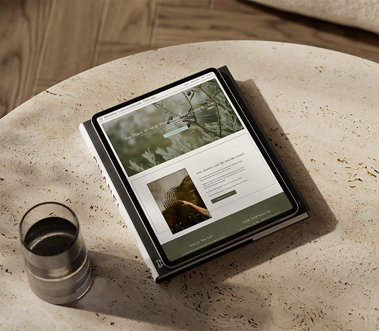 Tablet displaying a earthy themed website rests on a weathered stone table beside a metal coffee cup, creating a calm, rustic mood.