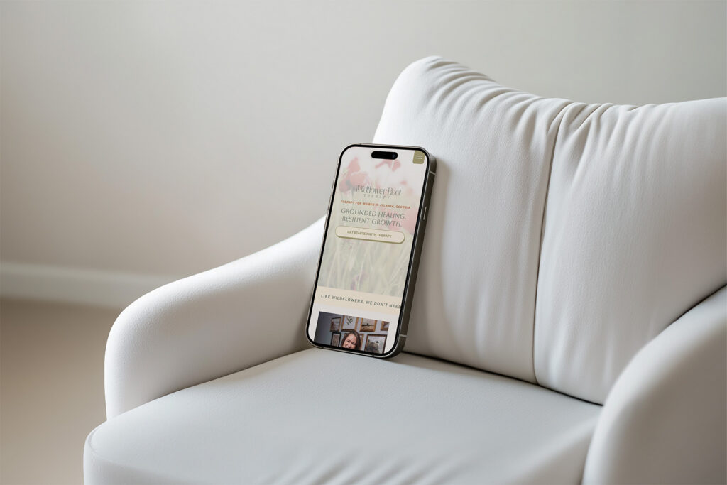 Smartphone displaying a social media page rests against a plush white armchair in a softly lit room, creating a calm, modern atmosphere.