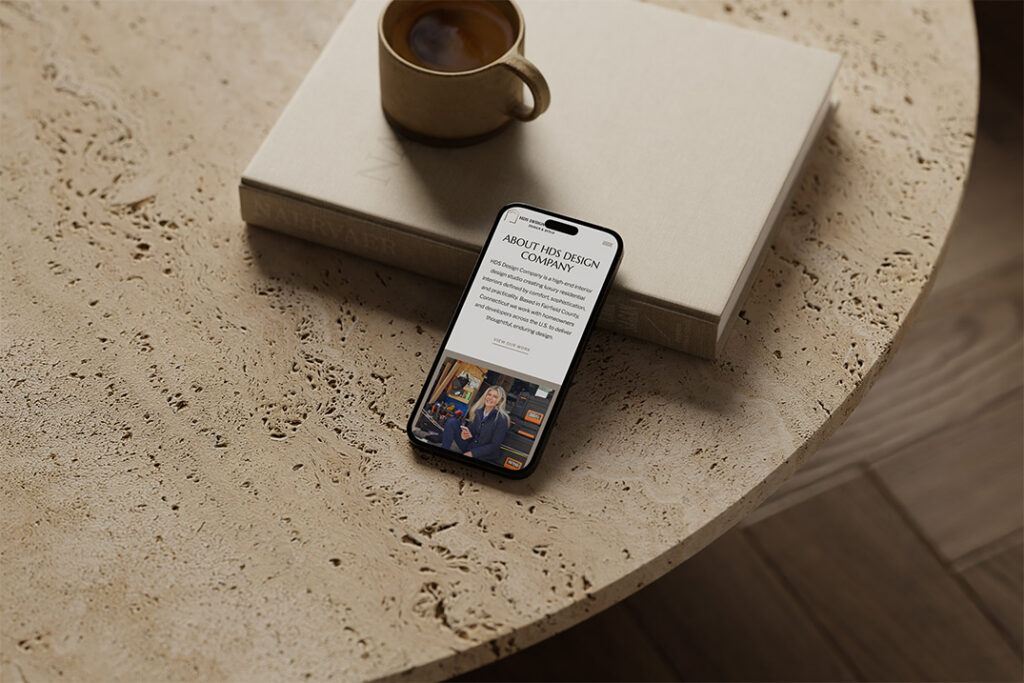 Overhead view of a smartphone displaying a news article beside a coffee cup and closed book on a textured stone table, calm, warm mood.
