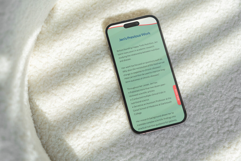 A smartphone displaying “Jen’s Previous Work” rests on a soft white textured blanket, creating a cozy, calm scene with gentle natural light.