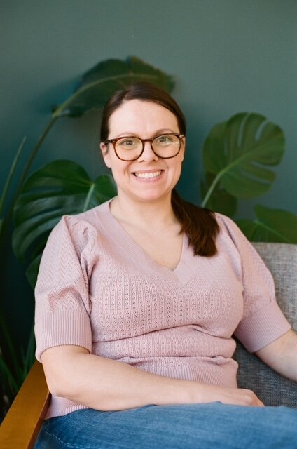 Kristen simons, wearing glasses and a pink shirt, smiling at the camera.