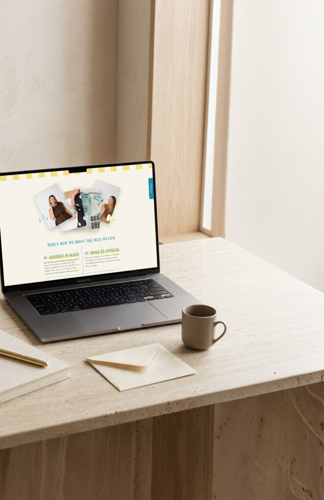Sunlit minimalist desk with an open laptop displaying a wellness website, a ceramic coffee cup, and a folded cream envelope; calm, uncluttered workspace.