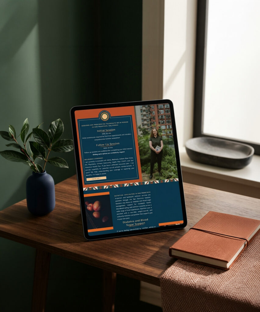 Tablet showing a teal-and-orange webpage with text and a portrait, propped on a wooden desk beside a plant and notebook in warm sunlight.