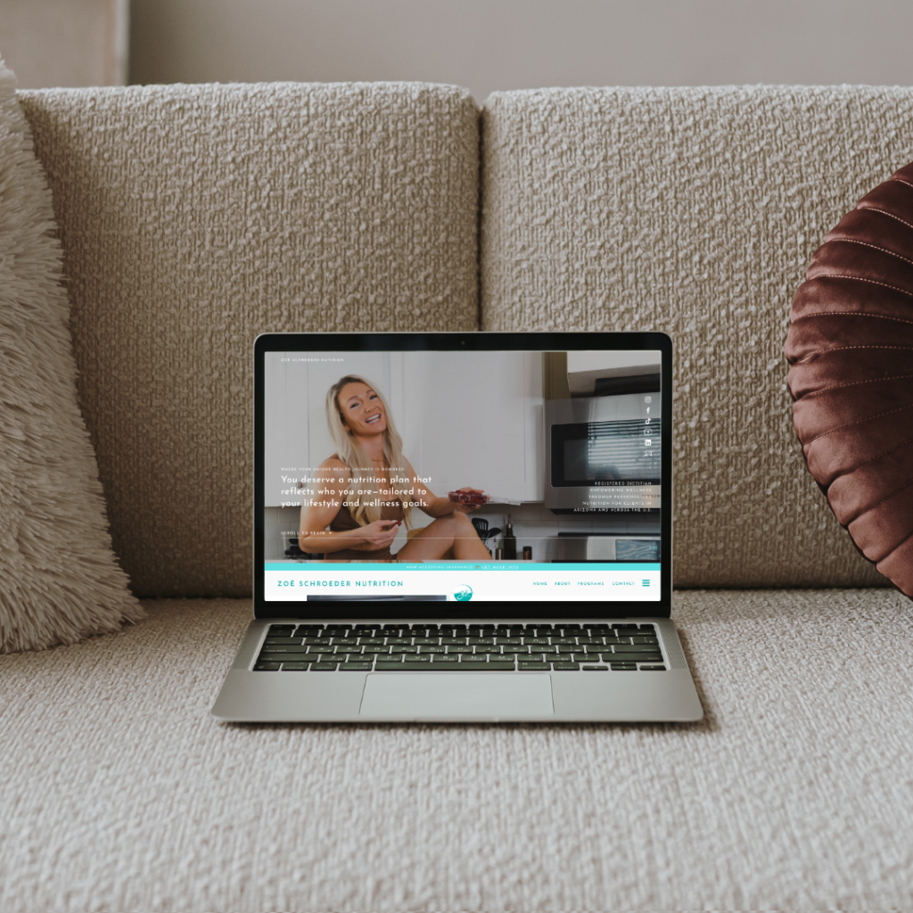 Laptop displaying a nutrition coaching website with a smiling woman in a kitchen, resting on a cozy textured sofa between decorative pillows.