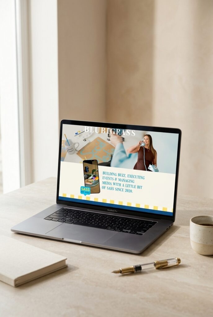 A laptop on a bright desk displays a Bluegrass promotional webpage with a woman, phone, and savings message; the calm, sunlit scene feels polished and inviting.
