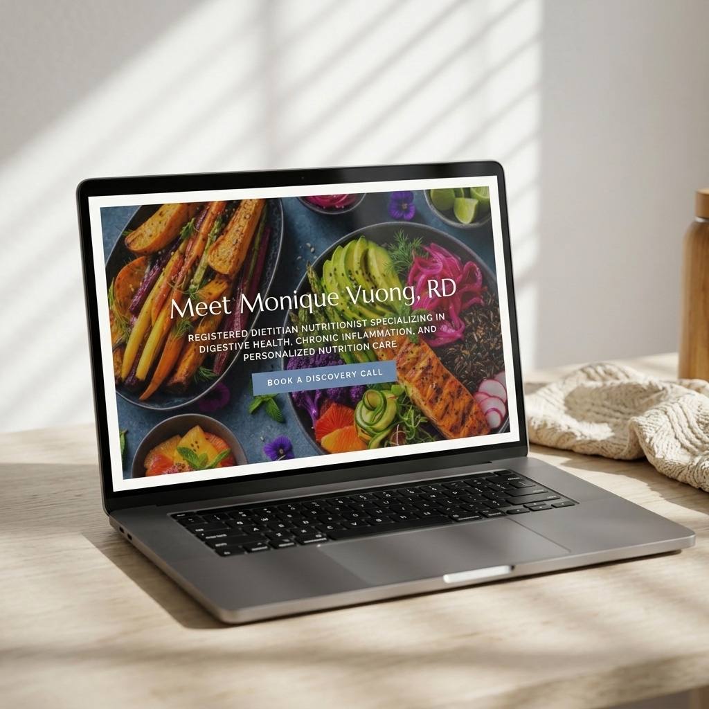 A sunlit laptop displays a colorful nutrition website for Monique Vuong, RD, a registered dietitian specializing in digestive health and personalized care.