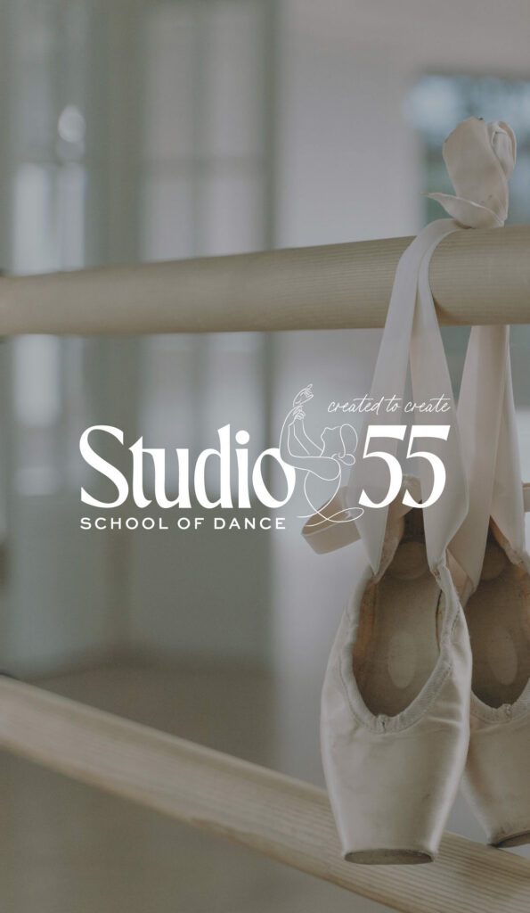 White satin ballet pointe shoes hang from a studio barre in soft light, beside “Studio 55 School of Dance” text, creating a calm, graceful mood.