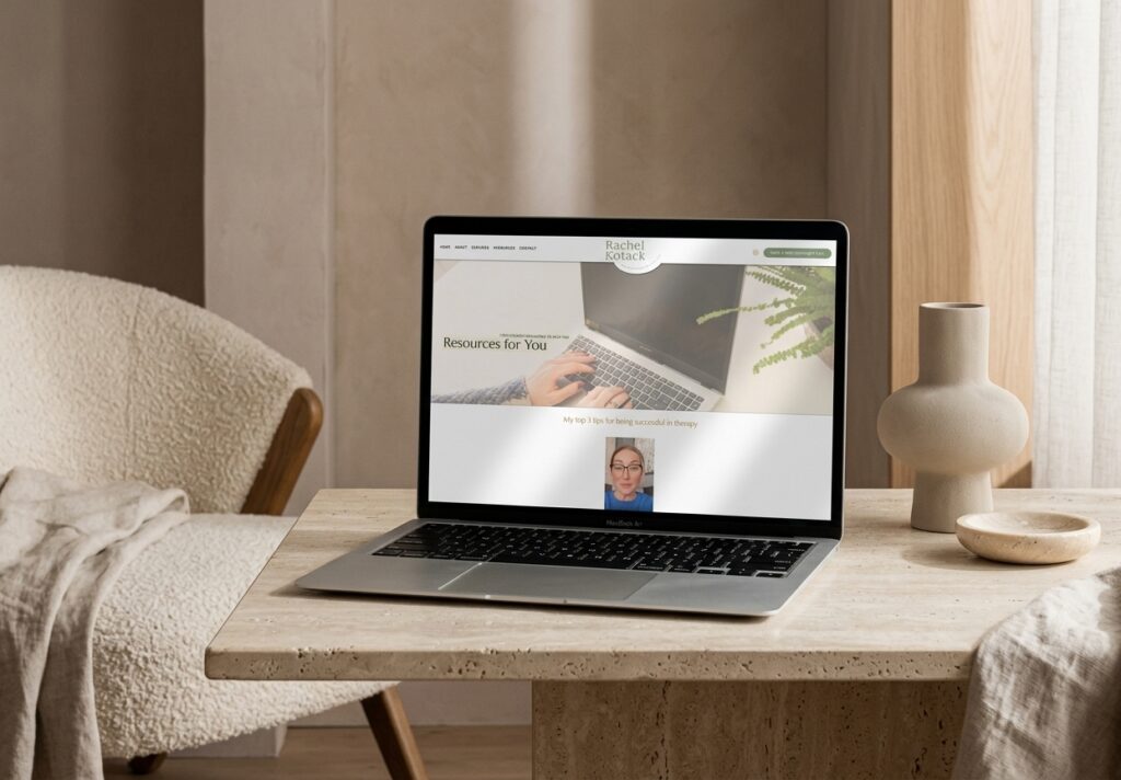 Warm home office scene with a laptop displaying an online resources page and video call, beside a vase and bowl on a wooden desk.