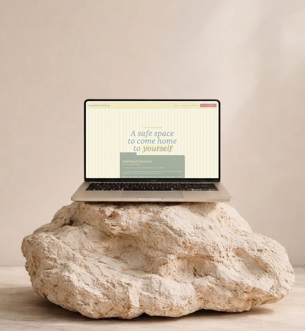 Laptop displaying “A safe space to come home to yourself,” balanced on a large textured rock; calm, minimalist scene with a reflective tone.