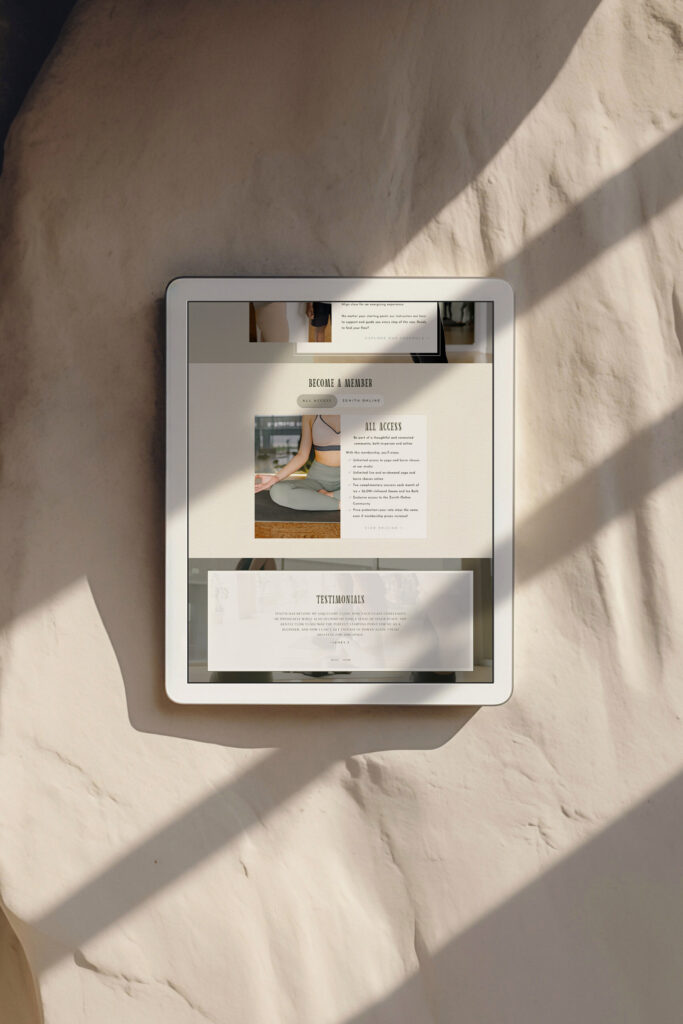 Tablet displaying an elegant luxury website with product imagery, “About” text, and testimonials, resting on wrinkled fabric in warm sunlight.