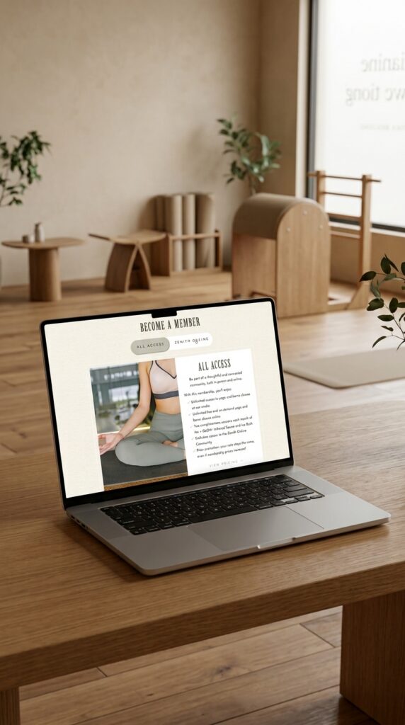Laptop displaying a wellness website with a seated yoga pose and class details on a wooden desk in a warm, plant-filled home office with natural light.