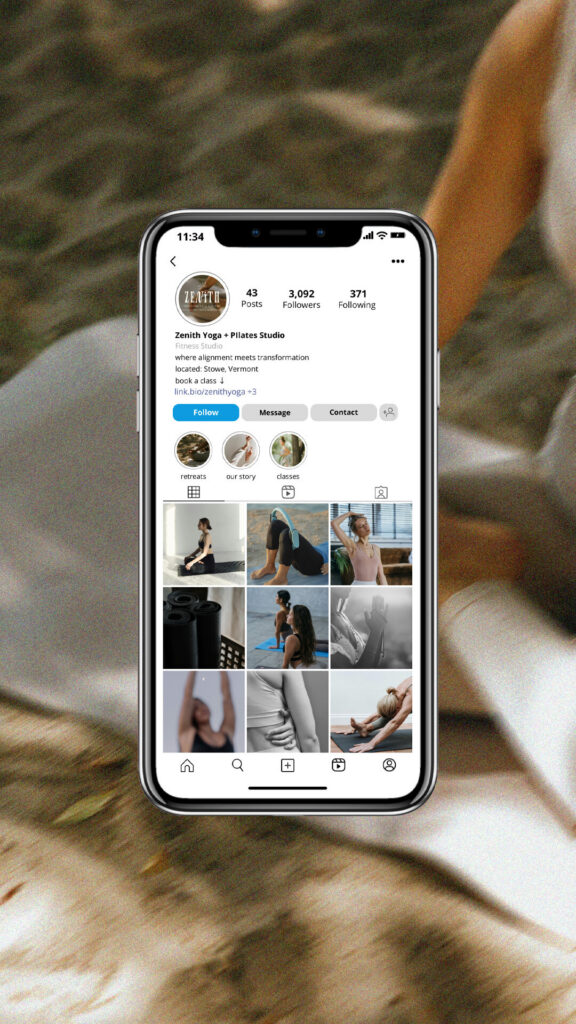 Close-up of a smartphone displaying a fitness influencer’s Instagram profile and workout photos, resting on a cozy beige blanket in warm light.