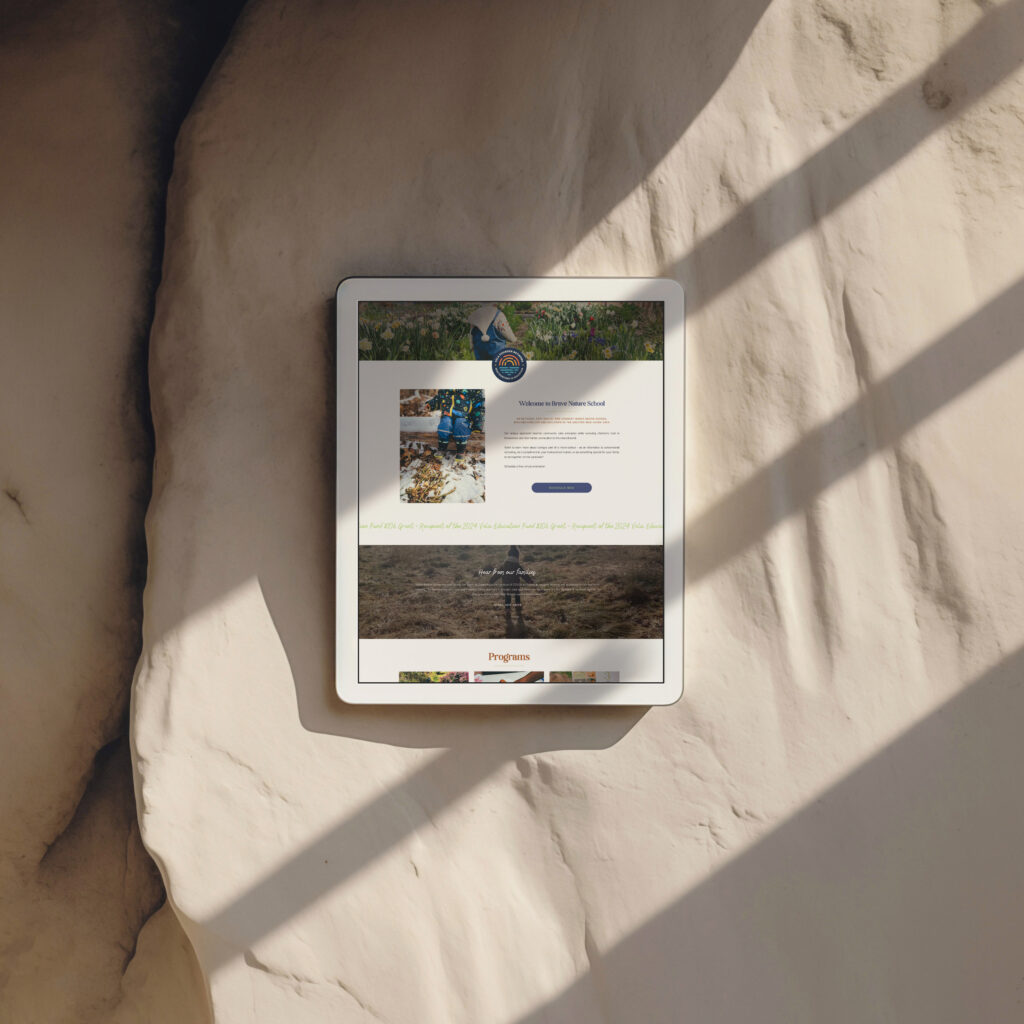 An overhead tablet displaying a botanical garden or nature project webpage rests on a pale sculpted stone surface, crossed by long diagonal shadows.