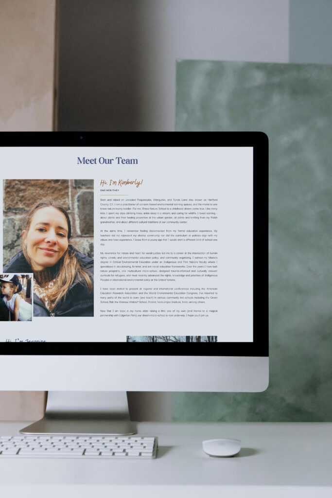 A desktop computer displays a “Meet Our Team” webpage with a woman’s portrait and biography, alongside a white keyboard and mouse in a calm workspace.
