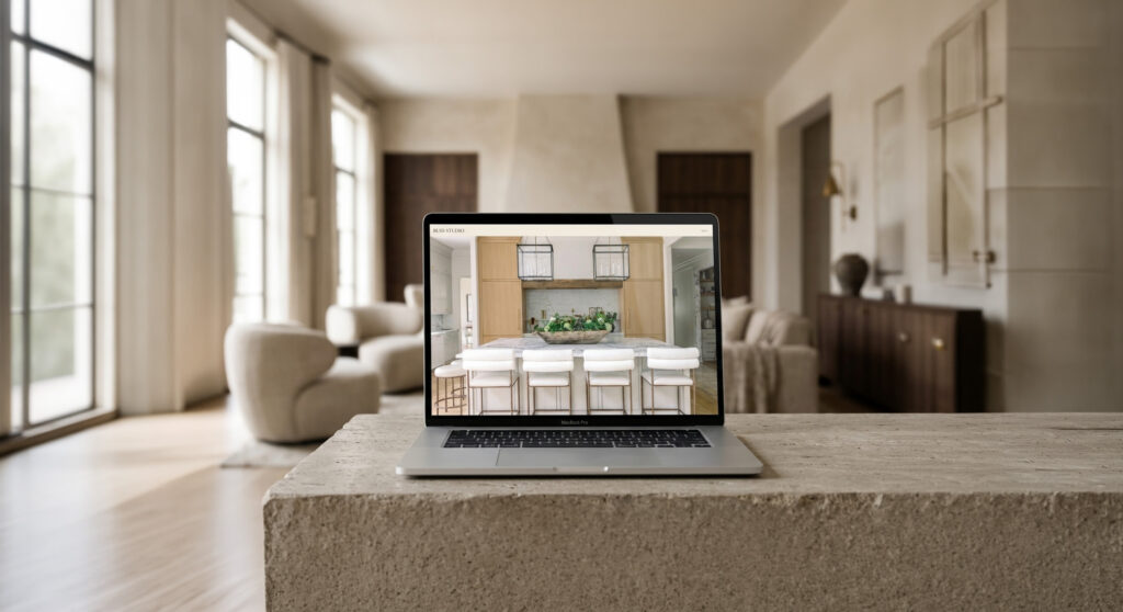 A laptop on a stone kitchen island displays a bright, modern kitchen; a sunlit open-plan home blurs behind it, creating a calm, inviting feel.