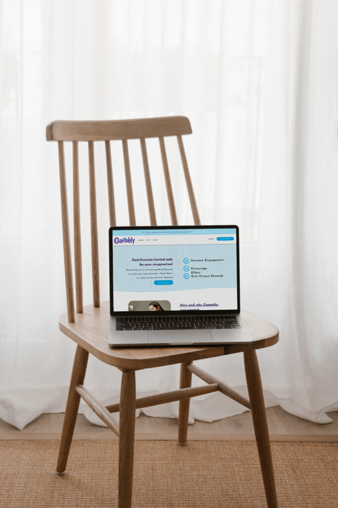 A laptop showing a blue-and-white webpage rests on a wooden chair in a bright room with sheer curtains, creating a calm, minimalist feel.